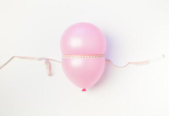 Balloon tied measuring tape on white background. Weight loss, slim body, healthy lifestyle concept. The waist measurement.