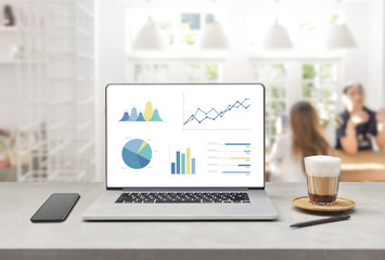 Laptop on wooden table showing charts and graph