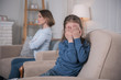 © Viacheslav Yakobchuk - Crying. Miserable dark-eyed girl sitting on the couch and her mother sitting in the background
