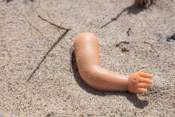 Broken doll hand in the sand