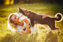 Small Husky Licks Joyful Blonde In Glasses With Ice Cream In Her Hands In The Summer In The Park