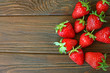 Handful of a strawberry harvest on a wooden background