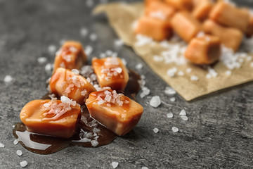 Wall Mural - Delicious candies with caramel sauce and salt on gray background