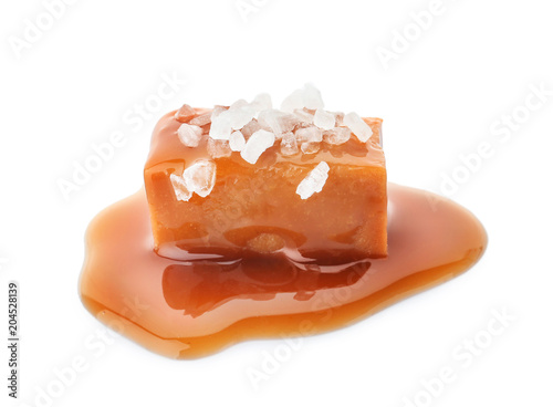 Plakat Delicious candy with caramel sauce and salt on white background