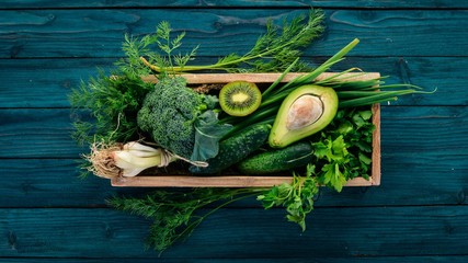 Fresh green vegetables and fruits in a wooden basket. Healthy food. Top view. Copy space.