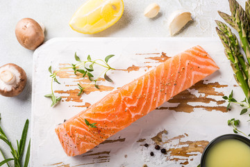 Wall Mural - Overhead shoot with fresh green asparagus, raw salmon fillet, herbs and sauce and old white wooden board. Healthy food background, copy space, top view.