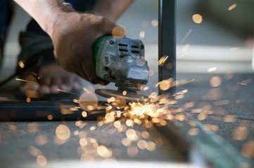 The worker is welding metal part of table steel in factory.