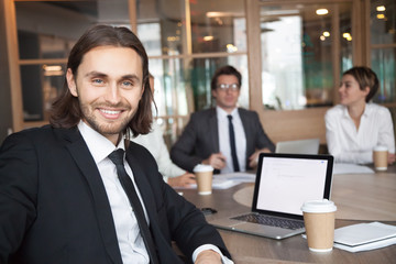  Smiling handsome young businessman in suit and tie looking at camera posing at group meeting with partners, happy executive manager, successful team leader or professional business coach portrait