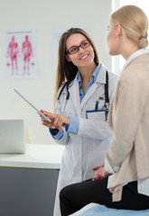 Doctor and patient discussing something while sitting at the table . Medicine and health care concept