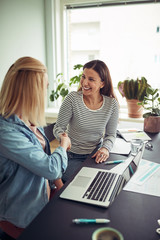 Two smiling businesswomen shaking hands together in an office