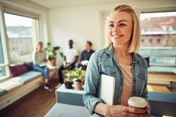 Wall Mural - Smiling young businesswoman drinking coffee during and carrying