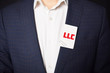 © Майя Руднева - Businessman shows business card with the inscription:LLC