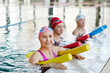 © pressmaster - Active senior women in swimwear holding equipment for water aerobics while training in swimming-pool