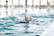 © pressmaster - Active mature woman in swimwear swimming and exercising in water at lesiure