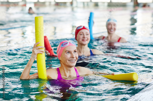 Fotografie, Obraz Smiling mature female in swimwear and two more active women listening to trainer