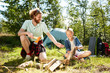 © pressmaster - Two young boyscouts sitting on grass and preparing firewood for making campfire