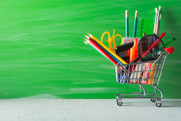Wall Mural - Shopping cart with stationery on green background