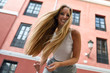 © javiindy - Happy young woman with moving hair in urban background.