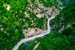 Aerial view  over mountain road and curves going through forest landscape