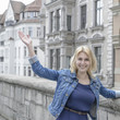 © igorgeiger - girl with blond hair and blue eyes is waving her hand in the old beautiful city.
