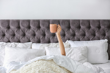 Poster - Woman with cup of coffee on bed at home