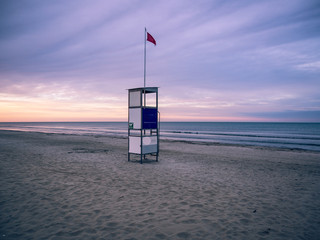 Wall Mural - Lifeguard stand on a deserted beach at sunset.