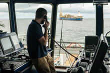 Deck Navigation Officer On The Navigation Bridge. He Speaks By VHF Radio, GMDSS Watchkeeping, Collision Prevention At Sea. COLREG