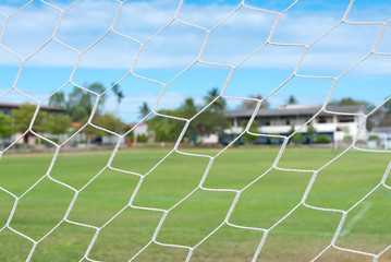 Dirty football net on the field with bright atmosphere.