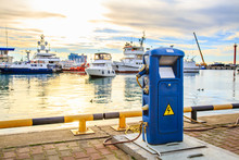 Charging Station For Boats, Electrical Outlets To Charge Ships In Harbor - Supply Electricity For Recharging Of Battery On Shore In Marina Jetty. Luxury Yachts Docked In Port At Sunset.