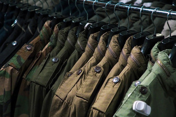 Things are men's clothes on hangers in a trendy clothes store. Clothes on a hanger in a fashion boutique. Selective focus. Shopping concept. men's military clothing khaki