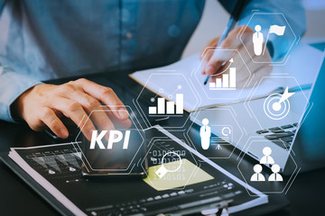 close up of businessman working with smart phone and digital tablet and laptop computer  on wooden desk in modern office with glass reflected view