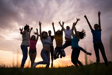 Wall Mural - Young people jumping against the sunset sky