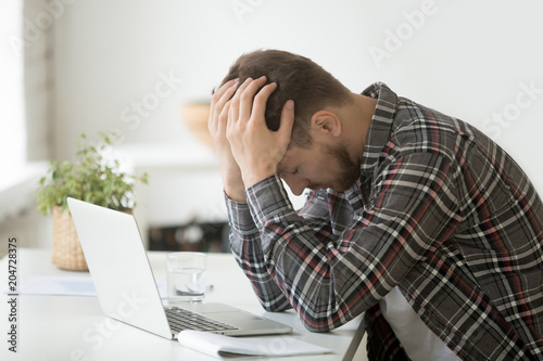Fotografía Frustrated depressed man holding head in hands shocked by bankruptcy stock downf