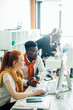 © alfa27 - close up side view portrait of African and Caucasian red-haired volunteers looking at the screen of the computer