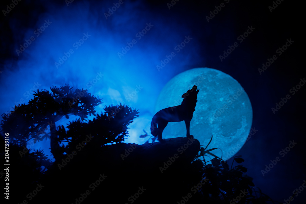 Obraz na płótnie Silhouette of howling wolf against dark toned foggy background and full moon or Wolf in silhouette howling to the full moon. Halloween horror concept. w salonie
