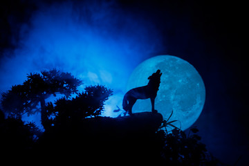 Naklejka na meble Silhouette of howling wolf against dark toned foggy background and full moon or Wolf in silhouette howling to the full moon. Halloween horror concept.