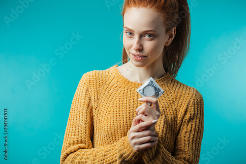 Cuadros en Lienzo Young redhaired woman showing condom in her hand , displaying her choice of safe pleasure and protection