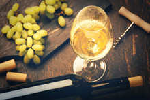 A Glass Of White Wine And Green Grapes On Wooden Background