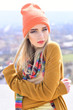 © Volodymyr - Young hipster with straight blond hair wearing orange hat and stripped multicolored scarf posing outdoors. Street fashion concept