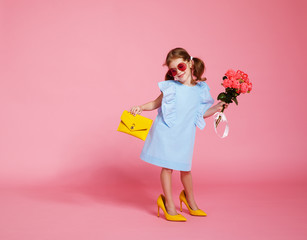 funny child girl fashionista in big mother's   shoes on colored background