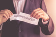 businessman Hand ripped card with word disorganized. concept to end chaos. disorganized is organized concept.