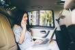 © F8  \ Suport Ukraine - Businesswoman sitting on back seat of car with laptop talking on mobile phone. Female executive travelling to work in luxury car.
