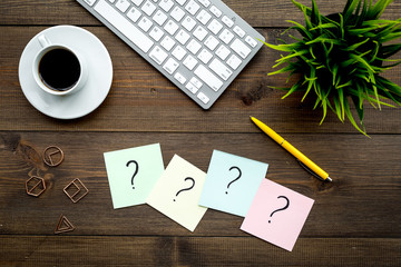 Poster - Question mark on sticky notes on office desk on dark wooden background top view. FAQ concept. Working with clients. Troubles in work.