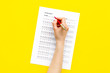 © 9dreamstudio - Take the exam, write the exam. Hand with pen near exam paper on yellow background top view copy space