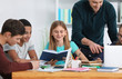 © Africa Studio - Group of teenagers doing homework with teacher in classroom