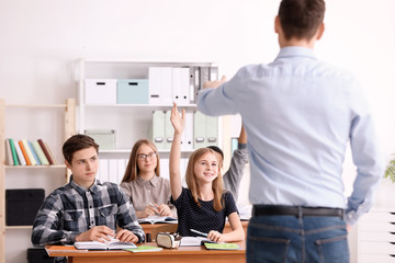 Wall Mural - Group of teenagers doing homework with teacher in classroom