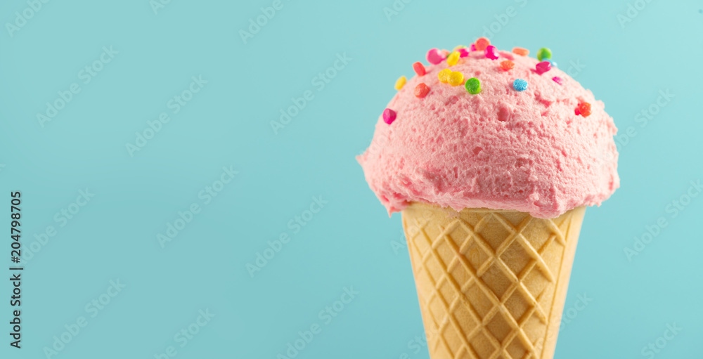 Ice cream. Strawberry or raspberry flavor icecream in waffle cone over blue background. Sweet dessert decorated with colorful sprinkles closeup - obrazy, fototapety, plakaty 