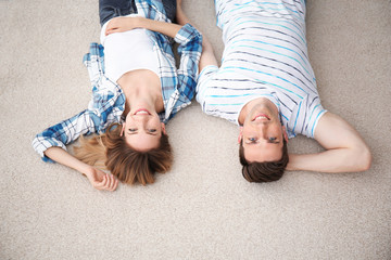 Sticker - Lovely young couple lying on cozy carpet at home