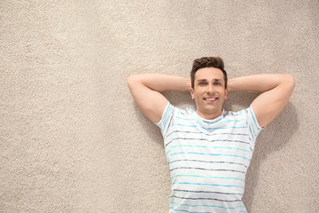 Sticker - Handsome young man lying on cozy carpet at home