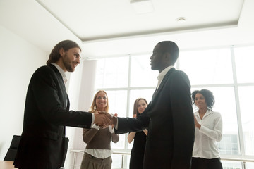 Wall Mural - boss and team appreciating successful black businessman by handshake applause, smiling leader awardi